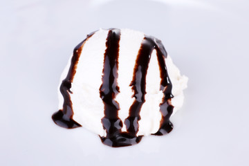 Vanilla ice cream with chocolate sauce on white plate, close-up