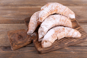 Tasty bagels with sugar powder, on wooden background