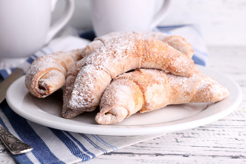 Tasty bagels with powdered sugar, on wooden background