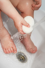 child washes hands and feet in a wash basin