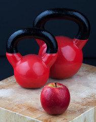 Fototapeta na wymiar Red apple and kettlebells on chopping board