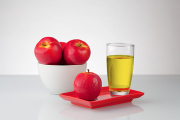Red apples and juice on reflective surface