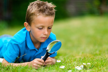 Boy with magnifying glass in garden