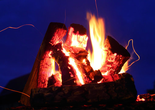 A bonfire and sparks over the dark blue sky extrim closeup
