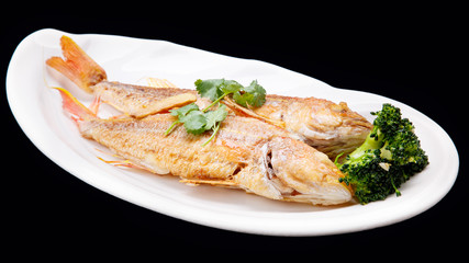 Frying Red Snapper Fish and broccoli isolated on black backgroun