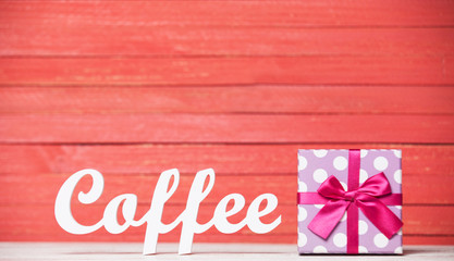 Abstract wooden word Coffee with gift on red wood background.