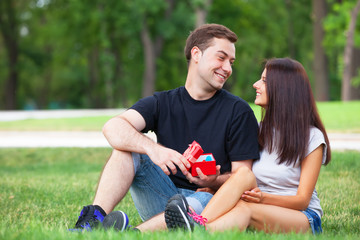 Teen couple with gift in the park.