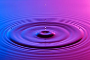 Naklejka na ściany i meble Water drop close up with concentric ripples colourful blue and p