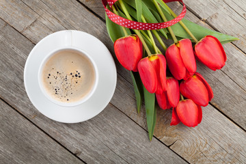 Fresh red tulips with ribbon and coffee cup