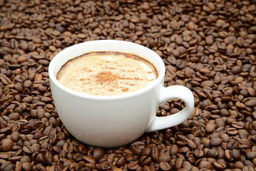 cup of coffee with cinnamon on a coffee beans background