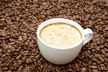 cup of coffee with cinnamon on a coffee beans background