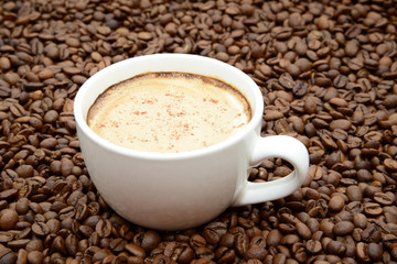 cup of coffee with cinnamon on a coffee beans background