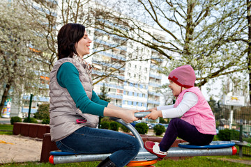 Mother with little daughter are playing at carousel