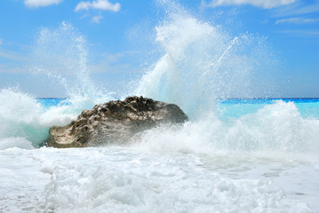 Big sea wave breaking on the shore rocks with a high sea spray