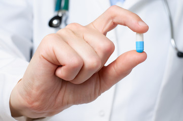 Doctor holding a blue a pill
