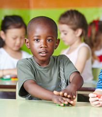 African child playing with dough in kindergarten