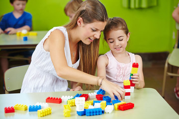 Nursery teacher and girl playing with building bricks