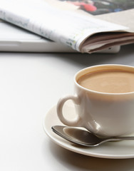 Cup of coffee near newspapers