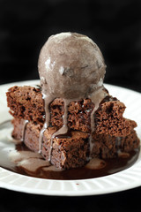 Slices of a brownie covered with chocolate ice cream