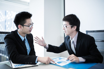 Two Businessmen Having Informal Meeting In Modern Office