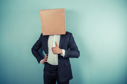 Businessman with box on his head giving thumb up