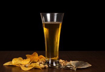 Chips, pistachios, salty fish and beer glasson