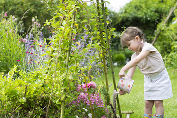 Petite Fille avec un arrosoir dans un jardin