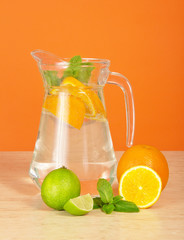 Jug with drink, orange and juicy lime