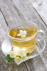 Obraz na płótnie Canvas cup of green tea with jasmine on wooden background