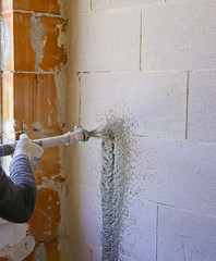 Worker performs internal plaster with machine applying plaster