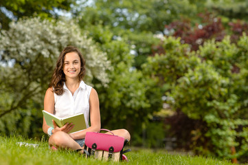 Student girl sitting grass with open book