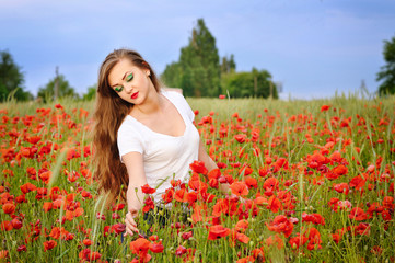 Fototapeta na wymiar Young beautiful girl in a poppy field