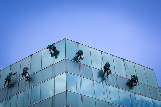 Group Of Workers Cleaning Windows Service On High Rise Building