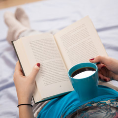 Woman reading a book and drinking coffee