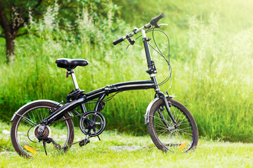 Black folding bicycle in grass