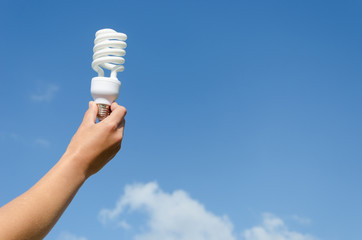 hand hold energy saving lamp blue sky background