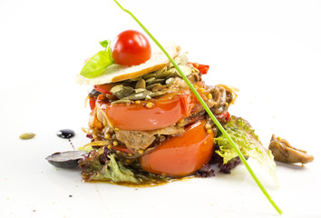warm salad of vegetables and meat on a plate in a restaurant