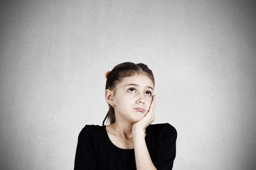 Sad daydreaming teenager girl isolated on grey wall background 