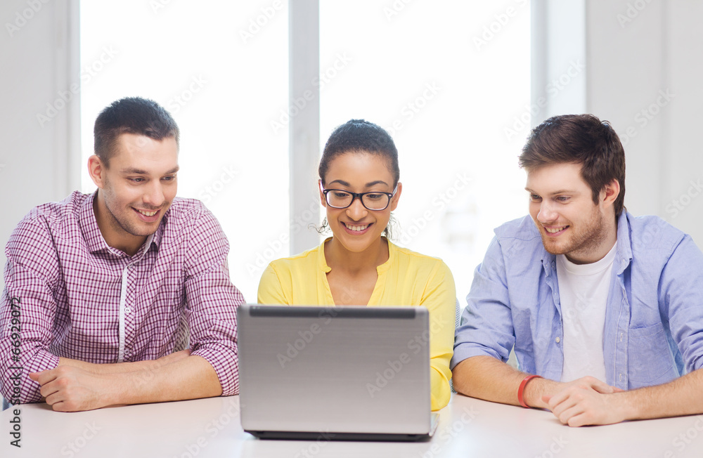 Canvas Prints three smiling colleagues with laptop in office