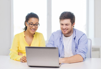 two smiling people with laptop in office