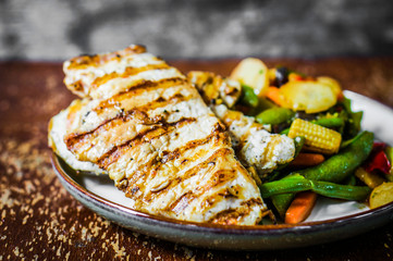 Grilled chicken with baked vegetables on rustic background