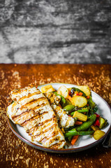 Grilled chicken with baked vegetables on rustic background