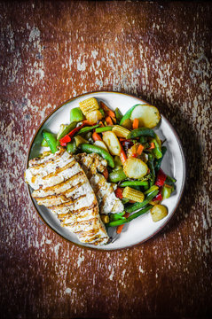 Grilled chicken with baked vegetables on rustic background