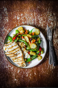 Grilled chicken with baked vegetables on rustic background