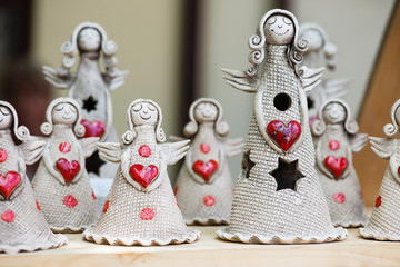 Group of ceramic angels with red heart on wooden table