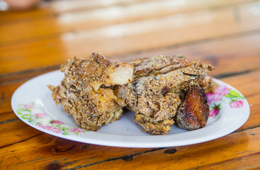 Fresh, fried chicken on a square white plate on a wood table
