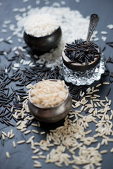 Raw brown, black and white rice kernels, close-up, studio shot