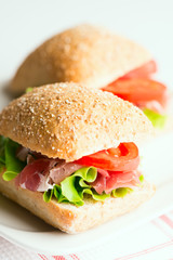 Prosciutto sandwiches with tomato and arugula on table
