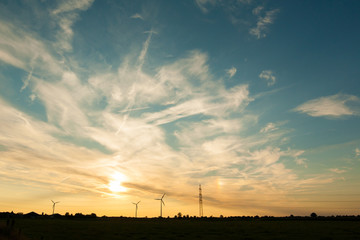 silhouettes of wind turbines with lots of sky