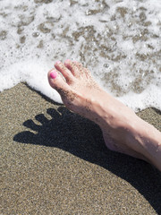 woman feet relaxing on the shore waiting for the sea foam